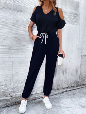 Dark blue cold-shoulder jumpsuit with drawstring waist and cuffed ankles.