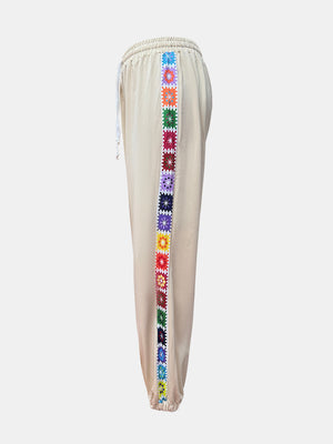 Tan jogger pants with colorful embroidered stripe detail down the side.