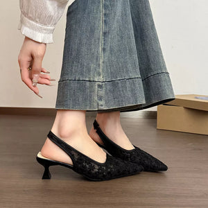 Black lace slingback kitten heels with a pointed toe and a kitten heel.