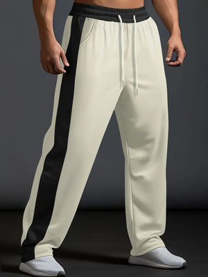 Beige track pants with black side panel detail and white drawstring.