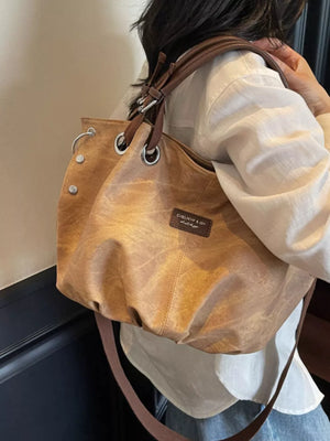 Slouchy crossbody bag in brown faux leather with adjustable strap and silver hardware.