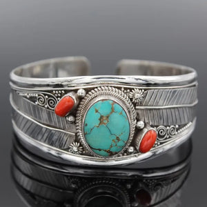 Turquoise cabochon open bangle with red accents and feather detail