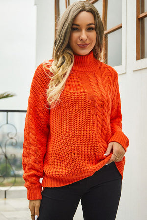 Orange cable-knit turtleneck sweater with voluminous silhouette and textured acrylic knit.