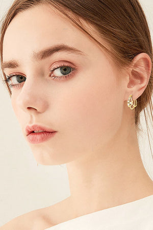 Gold hoop earrings with sculptural design and diamond accents.