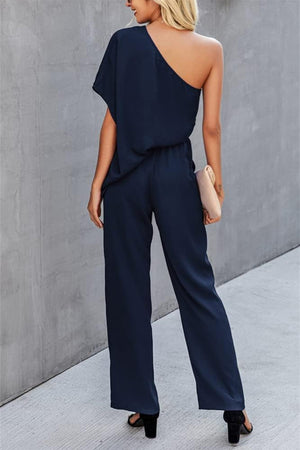 Dark blue asymmetric drape-sleeve wide-leg jumpsuit with elastic waist.