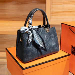 Elegant geometric embossed tote handbag in blue with a decorative scarf.