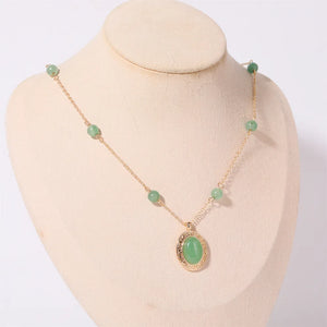 Gold chain necklace with neon green jade orb pendant and beaded accents.