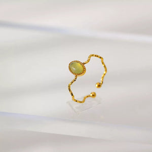 Wavy gold-plated ring with oval light green natural stone and adjustable band.