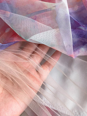 Floral tiered midi dress fabric detail in pink and purple watercolor print with smocked bodice texture.