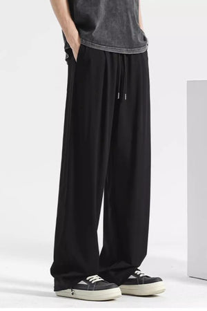 Black sweatpants with drawstring and pockets, styled with a t-shirt and sneakers.