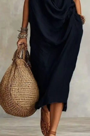 Black cowl neck midi dress with pockets and a woven tote bag.