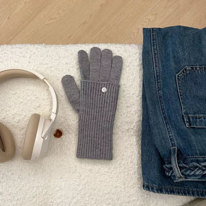 Gray ribbed knit convertible gloves with a button detail, shown with headphones and jeans.