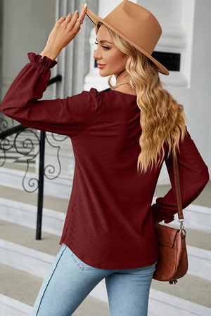 Burgundy textured puff sleeve blouse with ruffled cuffs.