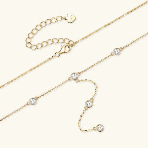 Gold lariat necklace with bezel-set moissanite drops and adjustable clasp.