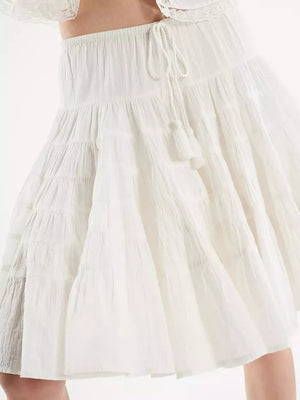 Tiered drawstring mini skirt in white with tassel detail.