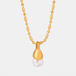 Gold necklace with oval beads and a teardrop pendant holding a pearl.