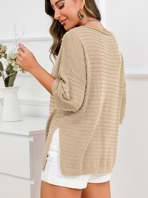 Tan knit sweater with boat neck, textured pattern, and slit hem detail.