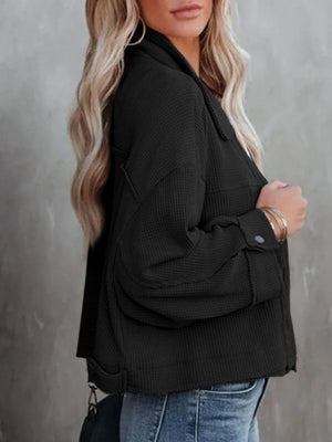Black waffle knit cropped utility jacket with buttoned cuffs and collar detail.