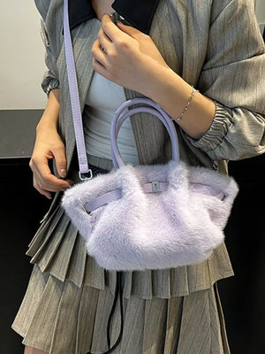 Plush purple crossbody bag with chic buckle detail and top handles.