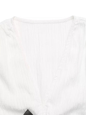 White crinkle fabric maternity blouse with V-neck and cap sleeves, featuring a bow detail.