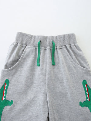 Grey cotton shorts with green dinosaur applique and drawstring waist.