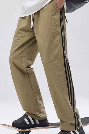 Khaki relaxed fit wide-leg sweatpants with black side stripes and drawstring waist.