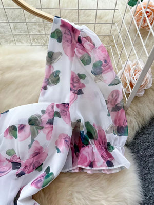 White cotton blend midi dress with pink floral print, puff sleeves, and ruffle hem.