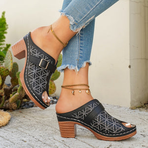 Black buckle sandals with floral embroidery and block heel, styled with distressed jeans.