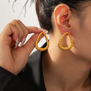 Gold rope-textured teardrop hoop earrings with a twisted design.
