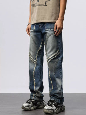Men's wide leg jeans in blue denim with frayed hem details and patchwork design.