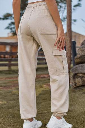 Tan utility cargo pants with elastic cuffs and multiple pockets.