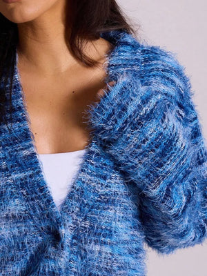 Blue textured knit cardigan with fuzzy yarn and a V-neck, worn over a white top.