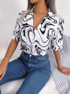 White blouse with black swirl print, camp collar, short sleeves, and button front.