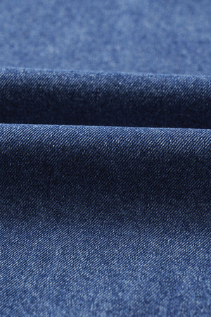 Utility denim mini dress in medium blue, showing fabric texture and folds.