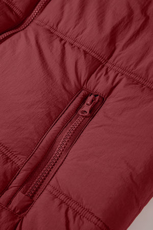 Burgundy quilted puffer vest detail showing a zippered pocket and stitching.
