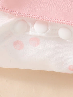Pink baby dress with white polka dots and snap closures