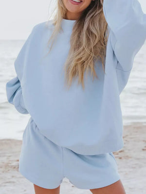Sky blue crew neck sweatshirt and shorts lounge set on a beach.