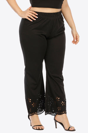 Black flare trousers with floral cutout hemline detail.