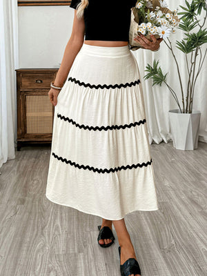 Elegant beige tiered midi skirt with wavy black trim and a textured fabric.