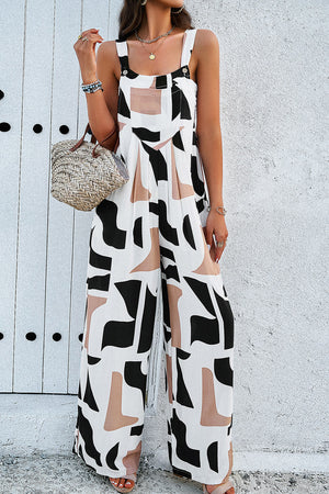 Abstract print wide leg jumpsuit in white with black and tan shapes, button straps, and wide legs.