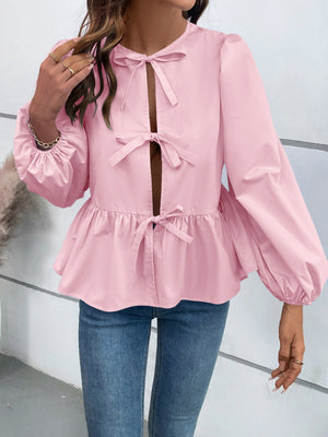Blush pink peplum blouse with keyhole neckline and bow details, long puff sleeves.