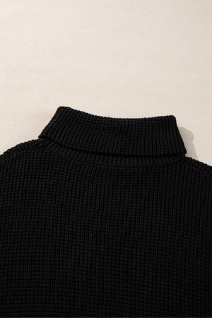 Black acrylic knit turtleneck sweater with ribbed texture and folded collar.