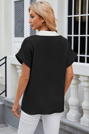 Black blouson top with white contrast V-neck and cuffed short sleeves.