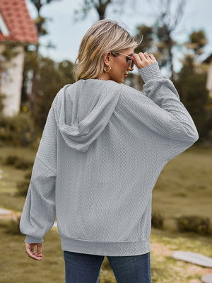 Grey textured knit dolman sleeve hoodie with cable knit pattern.