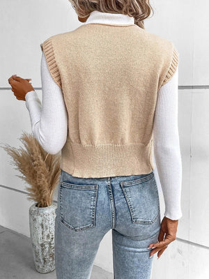 Tan acrylic knit vest with ribbed trim and hem, worn over a white turtleneck.