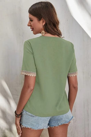 Light green V-neck blouse with lace trim on short sleeves.