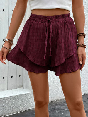 Burgundy tiered gauze drawstring shorts with ruffled hem detail.