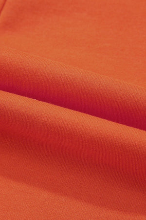 Orange colorblock romper with V-neck and patch pockets, close-up of fabric texture.