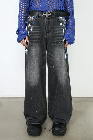 Dark wash denim jeans with painterly splatters and a wide flare leg.