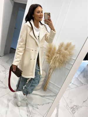 Cream suede effect overcoat with shearling trim and double-breasted closure.
